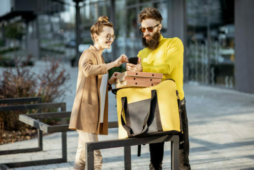 Man delivering pizza to a young woman client