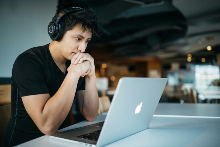 a person wearing headphones and sitting at a table with a laptop